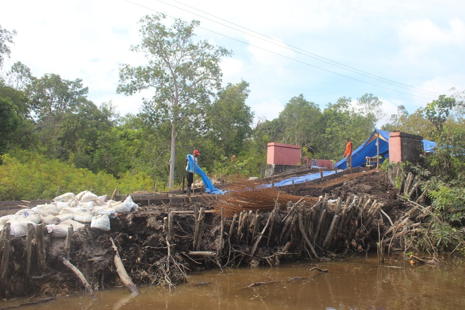 Di Bawah Gerimis, Satgas TMMD dan Warga Tetap Giat Pasang Besi Cor Jalan Desa Talio