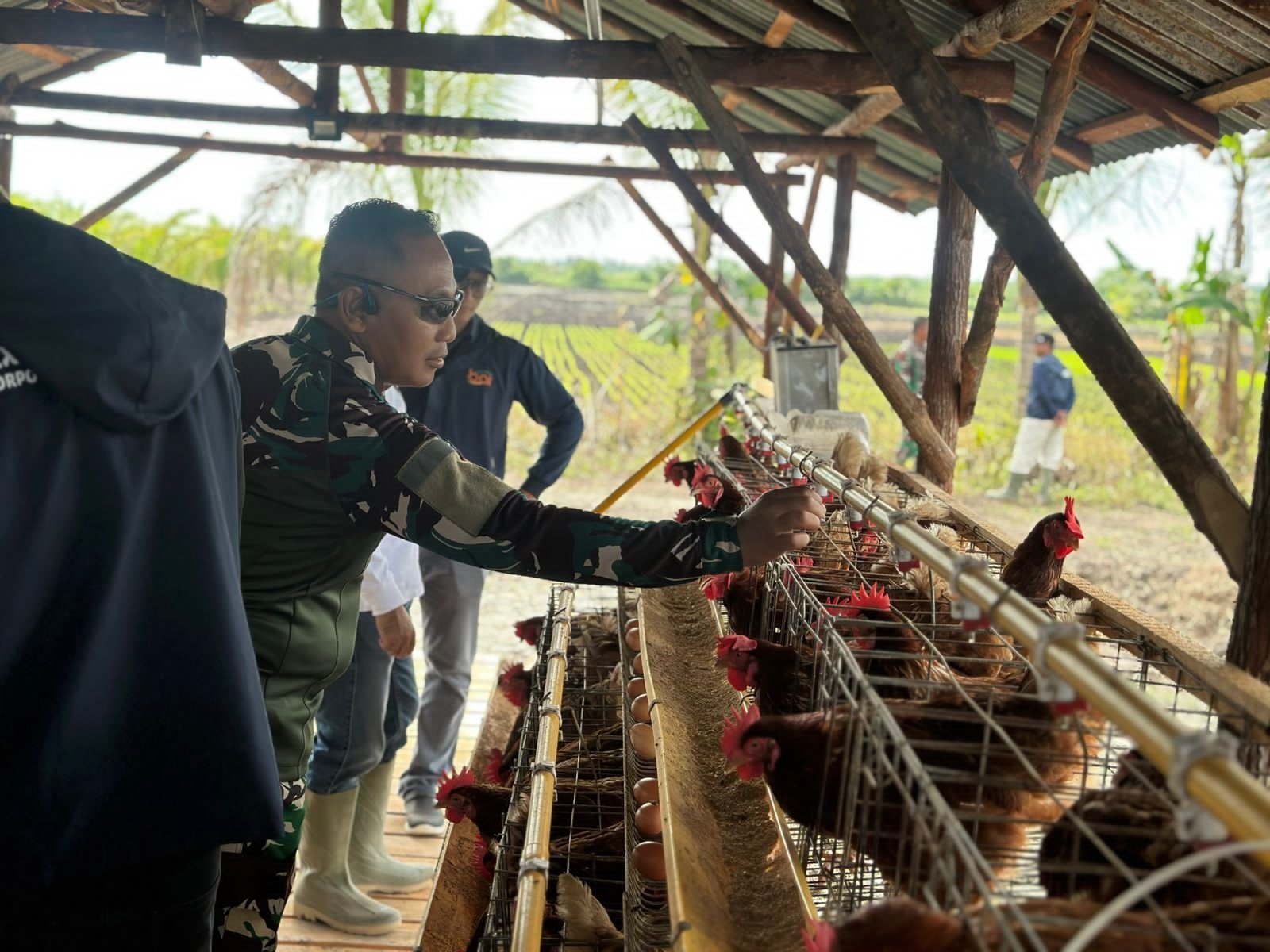 Dansatgas TMMD Perlihatkan Sistem Peternakan Ayam Petelur kepada Tim CSR PT. BAI